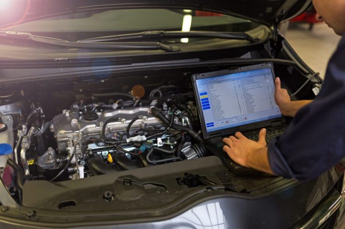 Diagnostic tools being used to evaluate engine performance and detect faults in a vehicle's system for repair purposes.