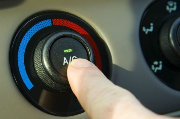 A mobile technician is servicing a car's air conditioning system by inspecting parts and recharging the refrigerant for optimal performance.